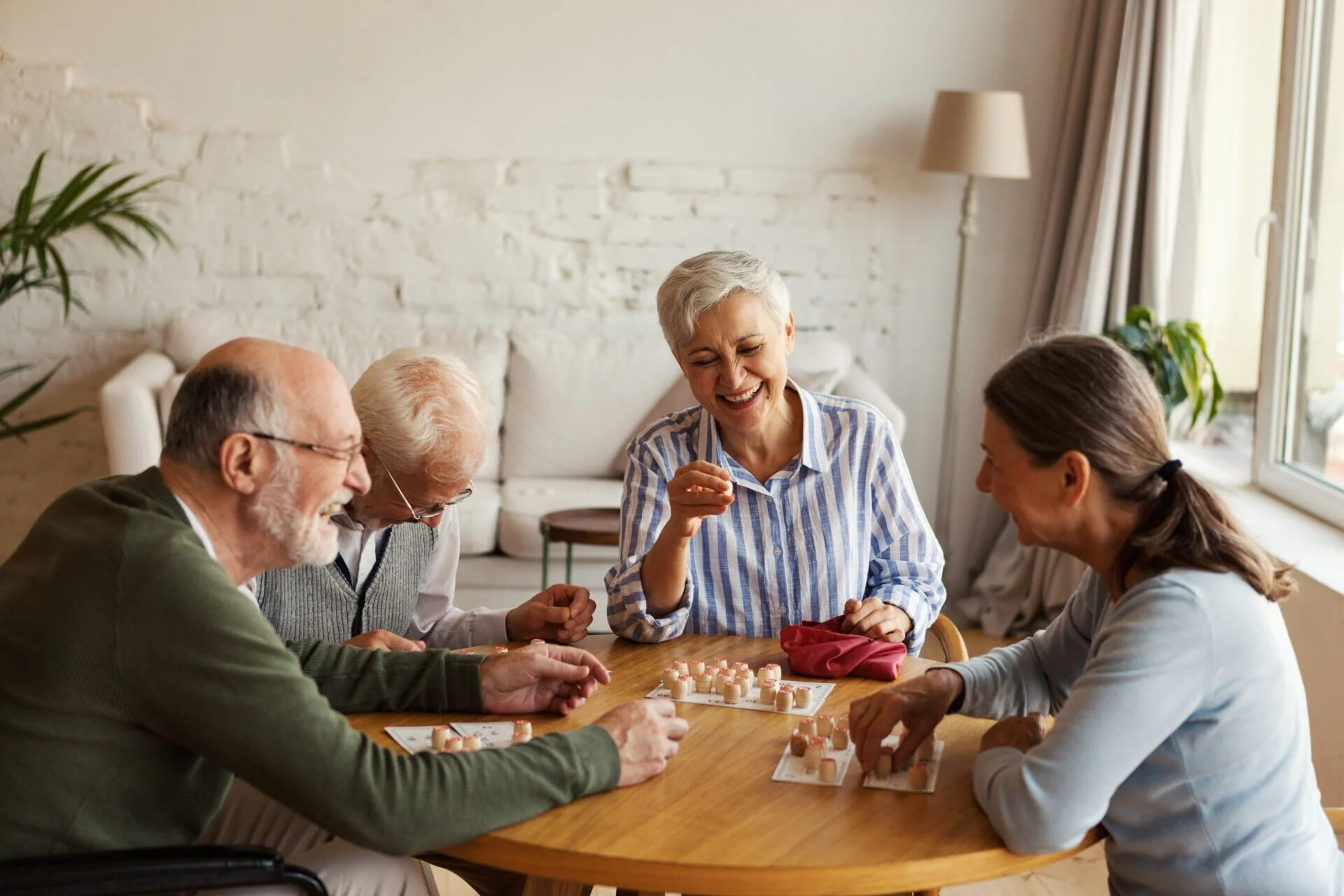 Un groupe de personnes âgées discutent. Ils sont quatre autour d’une table à échanger de manière conviviale.