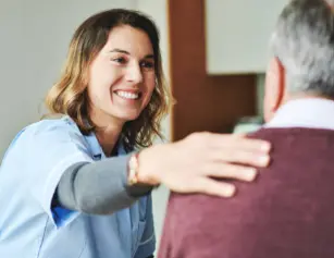 Une auxiliaire de vie réconforte un monsieur avec bienveillance